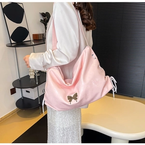 Dettaglio della borsa tote rosa lucida in ecopelle con farfalla in metallo e lacci bianchi