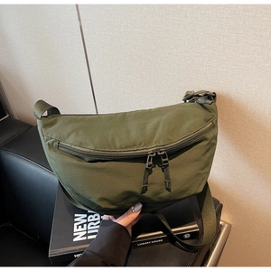 Detail of army green nylon crescent bag with durable double zippers and woven strap