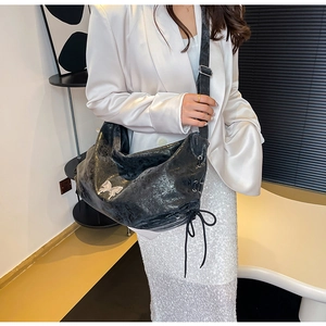 Dettaglio della borsa tote in ecopelle nera con logo a farfalla e coulisse laterale