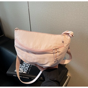 Close-up of pink canvas dumpling bag with double zippers and adjustable strap
