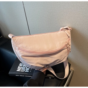 Detail view of the light pink nylon dumpling bag with adjustable wide fabric strap