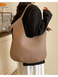 Minimalist camel tote bag with knot detail worn by a model in a cozy interior setting