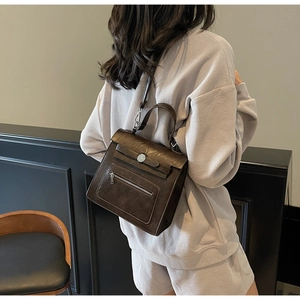 Detail of dark brown vintage leather handbag with silver clasp and slim shoulder straps
