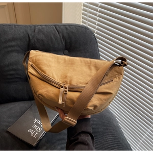 Detail of khaki canvas crescent crossbody bag with adjustable wide strap and zippers