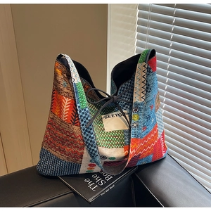 Detail of bohemian canvas tote with ethnic prints and SEEYOU label on a leather sofa