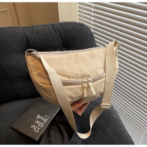 Detail of cream canvas dumpling bag with double zipper pockets and wide strap