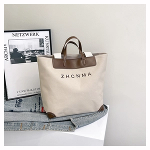 Detail of canvas tote bag with leather trim and ZHCNMA logo on elegant white display