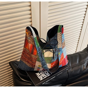 Detail of colorful patchwork tote bag with wide strap and SEEYOU label on black sofa