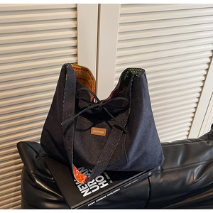 Detail of blue denim tote bag showing interior colorful printed lining and leather logo tag