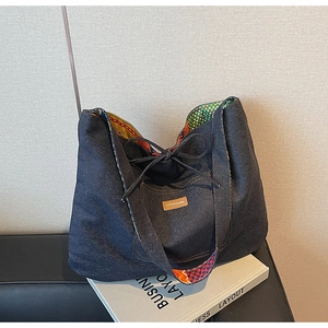 Detail of denim tote bag showing the textured fabric, brand label, and colorful lining