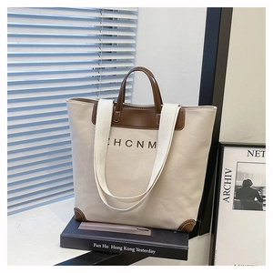 Detail of canvas tote bag with leather handles and HCNM logo on artistic background