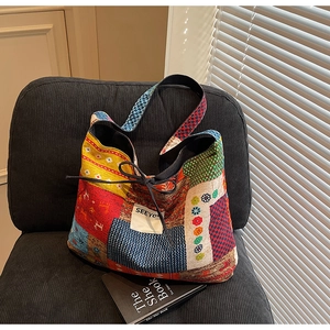 Close-up of a vibrant patchwork canvas tote bag with ethnic floral patterns on a black chair
