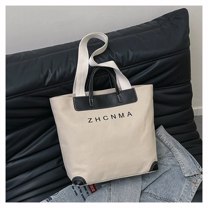 Detail view of large canvas tote bag with black leather reinforcement and ZHCNMA logo
