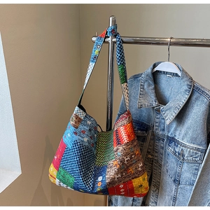 Close-up of bohemian patchwork tote bag hanging on hanger with casual denim jacket