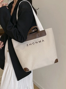 Large beige canvas tote bag with brown leather trim and ZHCNMA logo on model