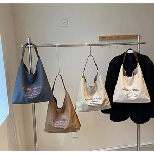 Détail de grands sacs cabas en toile en quatre couleurs neutres avec bretelles en cuir