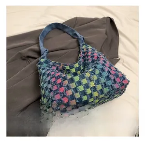Close-up of colorful woven plaid tote bag with denim straps and fringe edge details