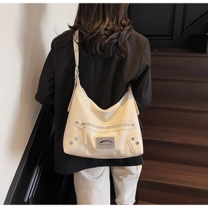 Detail of cream tote bag with silver studs and Noronoro metal logo in minimalist style