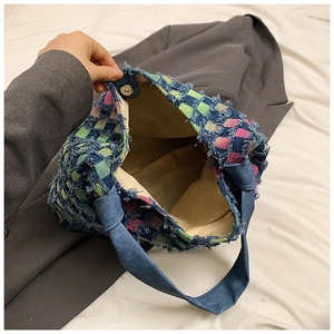 Detail of frayed edge denim tote bag with plaid pattern and magnetic closure design