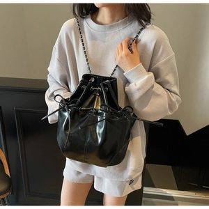 Close-up of black glossy bucket backpack with drawstring closure and chain strap detail
