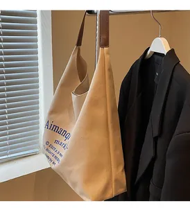 Détail du sac cabas en toile montrant le tissu crème et la bandoulière en cuir marron