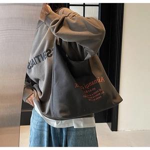 Détail du grand sac cabas en toile gris foncé avec une tenue streetwear minimaliste