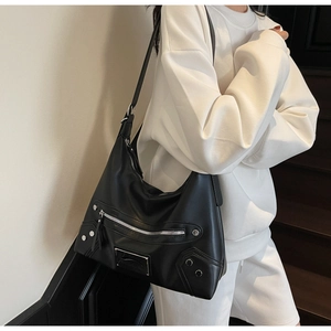 Model wearing a black punk-style shoulder bag with silver studs and zipper details