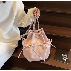 Detail of light pink PU leather bucket bag with bow drawstring and silver chain strap