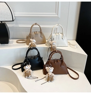 Minimalist shell-shaped crossbody bags in four colors with plush bear charms and top handles
