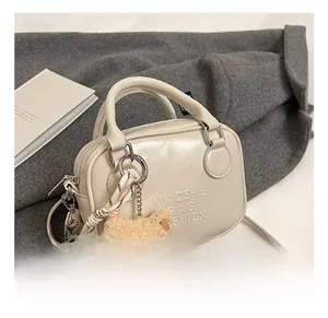 Detail of cream PU leather boston bag with MIAOSHE branding and cute bear charm