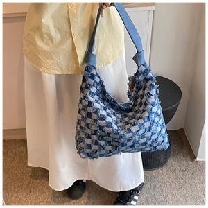 Detail of blue denim tote bag with patchwork checkerboard pattern and frayed edges