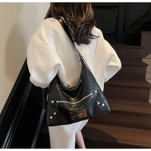 Detail of a black leather tote bag featuring silver studs and Noromoro metal plaque