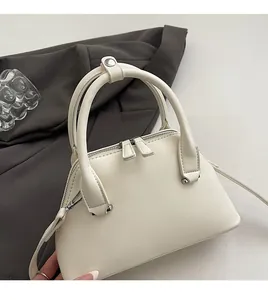 Detail of off-white shell bag showing smooth faux leather texture and silver hardware