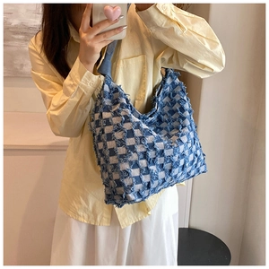 Detail of checkered denim tote bag with textured frayed edges and distressed fringe finish