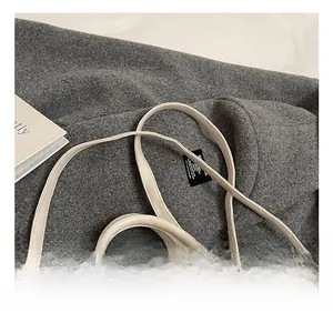 Detail of adjustable slim leather shoulder strap on cream-colored handbag with fine texture
