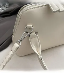 Close-up of creamy white leather bag showing silver metal hooks and fine stitching