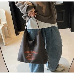 Détail du sac cabas en toile marron foncé avec lettrage artistique imprimé en rouge