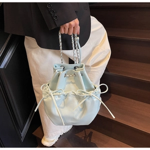 Detail of light blue bucket bag with decorative bows and silver chain leather strap