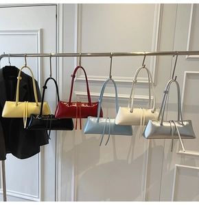 Modern rectangular baguette bags shown in six bright colors hanging on a metal rack