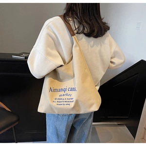 Grand sac cabas en toile avec bandoulières en cuir marron porté par un mannequin
