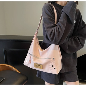 Detailed close-up of pink faux leather shoulder bag with zipper and metal rivet hardware