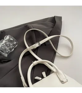Detail view of cream white leather bowling bag showing adjustable straps and silver hardware