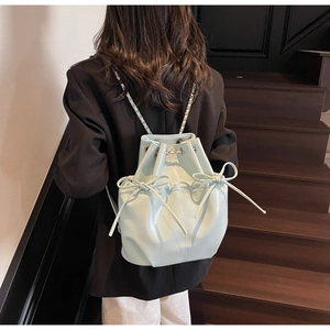 Detail of light blue bucket backpack featuring bow accents and silver chain straps