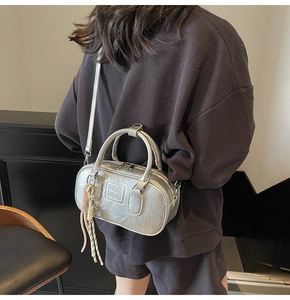 Sac bowling argenté métallisé avec lettres gaufrées et pompons porté à l'épaule