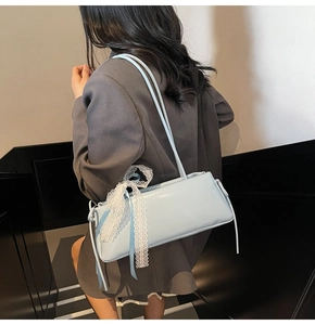 Detail of light blue shoulder bag featuring a white lace bow on the strap and smooth PU finish
