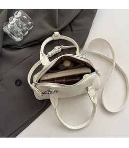 Top view of cream shell bag showing spacious brown lining with phone and long wallet inside