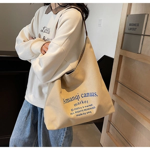 Détail d'un grand sac cabas en toile beige avec impression de lettrage bleu foncé