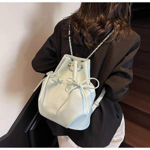Rear view of mint green drawstring bucket backpack with bow details on a model