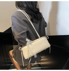 Detail view of cream shoulder bag featuring elegant side lace and bow decoration
