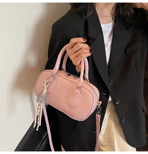 Gros plan du sac Boston rose avec logo UOR UOR, porté par un mannequin en costume noir